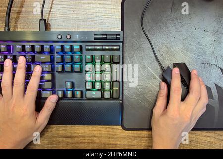 Gros plan mains de joueur qui utilisent le clavier de jeu mécanique et la souris de jeu pour jouer sur ordinateur PC Desktop sur la vue de dessus, e-sport Banque D'Images