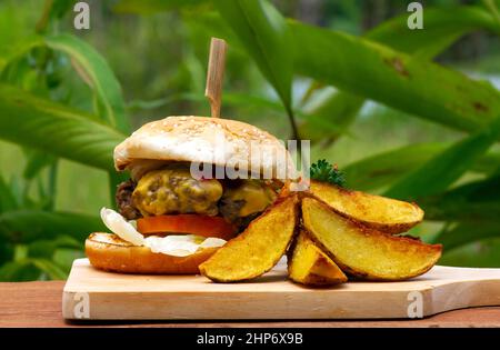 Savoureux hamburger de bœuf avec laitue et oignon servi avec des pommes de terre frites sur une table en bois Banque D'Images