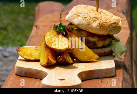 Savoureux hamburger de bœuf avec laitue et oignon servi avec des pommes de terre frites sur une table en bois Banque D'Images