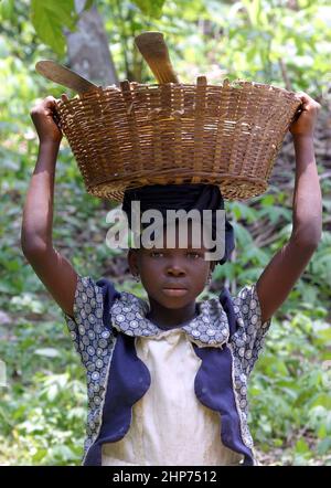 Enfant avec panier sur la tête plein de machette et de panga pour couper. Ghana Afrique de l'Ouest. Photo: Garyroberts/worldwidefeatures.com Banque D'Images