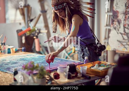 Femme indienne souriante dessinant sur une toile dans un studio d'art.ambiance créative. Banque D'Images