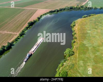 Un petit remorqueur pousse la barge le long de l'eau calme au-delà des champs Banque D'Images