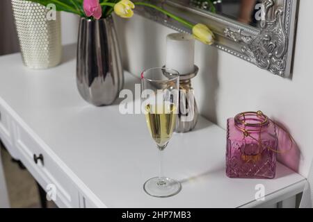 Un verre de vin blanc se trouve sur la coiffeuse de la chambre. Banque D'Images