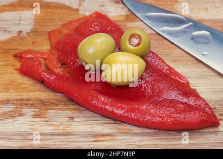 Olives vertes farcies et poivron rouge en planche à découper. Banque D'Images