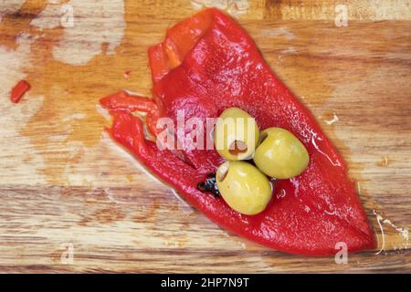 Olives vertes farcies et poivron rouge en planche à découper. Banque D'Images