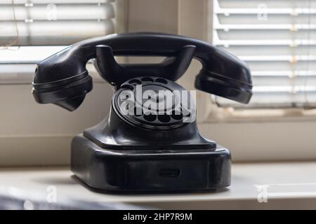 Un vieux téléphone rétro noir avec combiné est sur le rebord de la fenêtre. Banque D'Images