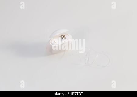 Une boîte blanche avec fil dentaire se trouve sur une table blanche. Banque D'Images