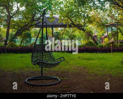 Chaise de jardin à bascule en rotin et osier pendu cadre dans un jardin Banque D'Images