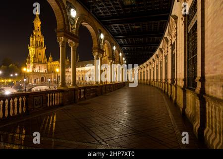 Place espagnole - Une vue nocturne à grand angle de l'aile nord éclairée d'un bâtiment semi-circulaire en briques de la place espagnole - Plaza de España, Séville, Espagne. Banque D'Images