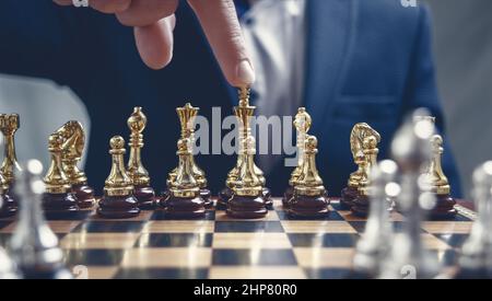 Homme d'affaires pointant du doigt une figure d'or Chess King. Stratégie, gestion, planification des activités et concept de leadership efficaces. EF rétro. Ton Banque D'Images