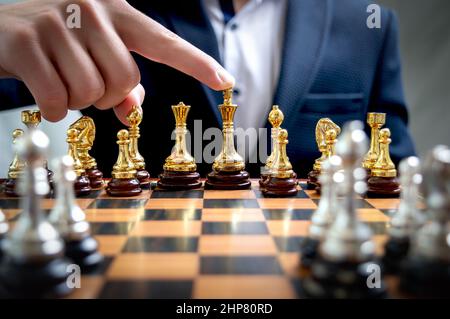 Homme d'affaires en costume joue aux échecs. La main pointe vers le gagnant, touchant la figure d'or Chess King. Stratégie d'affaires, brainstorming, conc. Du chef d'équipe Banque D'Images