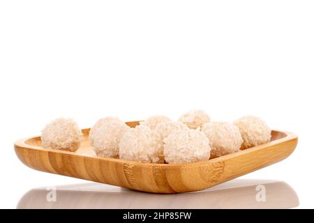 Quelques sucreries de noix de coco sucrées sur un plateau de bambou, macro, isolé sur un fond blanc. Banque D'Images