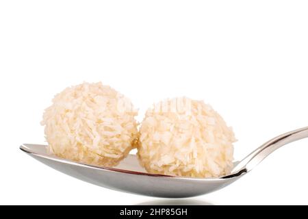 Deux sucreries de noix de coco sucrées dans une cuillère en métal, macro, isolées sur un fond blanc. Banque D'Images