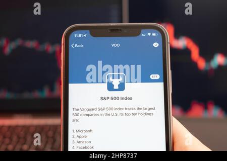 SP 500 baisse du prix des actions indiciels sur le marché de négociation avec graphique à barres de tendance descendante à l'arrière-plan. Homme tenant un téléphone portable avec le logo de la société, février 2022, San Francisco, Etats-Unis. Banque D'Images