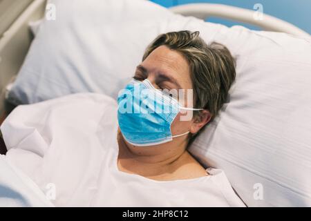 Une femme en masque dormant sur le lit d'hôpital Banque D'Images