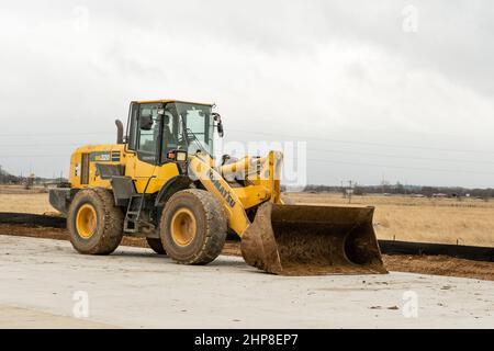 Grand chargeur sur roues jaune Kubota installé dans la rue à côté du chantier de construction. Banque D'Images
