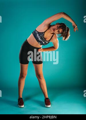 Une femme aux cheveux sombres s'encadre dans un short sportif et fait de la gym et s'étire les jambes Banque D'Images