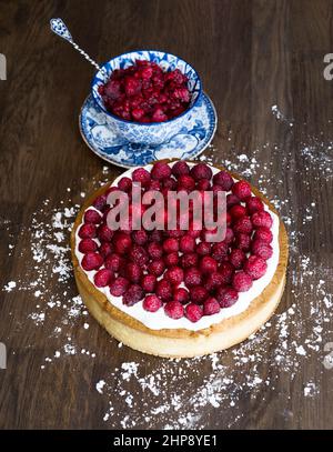 Gâteau à la framboise et bol en porcelaine bleue de framboises sur une table en bois Banque D'Images