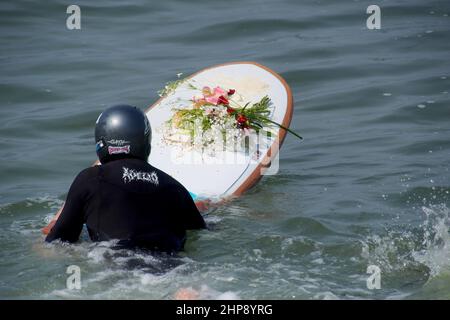 Un surfeur porte une offrande de fleurs sur son plateau quand, En guise de protestation contre la marée noire de Repsol qui a provoqué une catastrophe écologique sur les côtes de Lima et El Callao, un groupe de militants a organisé une cérémonie de mariage avec la mer sur la plage de Makaha à Lima. Le 15th janvier, plus de 10 000 000 barils de pétrole ont été déversés dans la mer à la raffinerie de la Pampilla exploitée par Repsol, une compagnie pétrolière espagnole, qui a produit l'une des plus grandes catastrophes écologiques du Pérou. Banque D'Images