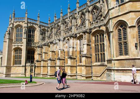 Un gros plan de l'architecture gothique de la chapelle Saint-Georges au château de Windsor, Berkshire, Royaume-Uni. Les visiteurs se tiennent à l'extérieur avec des casques et des guides audio. Banque D'Images