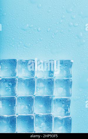 Beaucoup de glaçons glacés et rafraîchissants avec des gouttes sur fond bleu. Boissons rafraîchissantes par temps chaud Banque D'Images