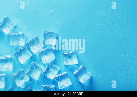 Glaçons avec gouttes d'eau dispersées sur fond bleu, vue du dessus Banque D'Images