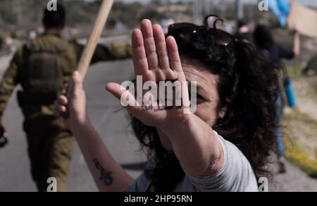 Une militante de gauche israélienne lève la main pour révéler les mots "fin de l'occupation" écrits sur sa paume lors d'une protestation contre la rétablissement de l'avant-poste illégal d'Eviatar près de la ville palestinienne de Naplouse le 18 février 2022 en Cisjordanie, Israël. Le procureur général d'Israël a approuvé la légalisation rétroactive de l'avant-poste d'Eviatar, ce qui signifie que le gouvernement israélien peut donner la zone aux colons. Banque D'Images