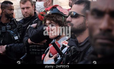 Un activiste israélien portant un costume de police et le nez rouge d'un clown se tient parmi les policiers pendant qu'ils regardent pendant une manifestation tenue par des activistes de gauche et des Palestiniens contre l'occupation israélienne et les activités de colonisation dans le quartier de Sheikh Jarrah le 18 février 2022 à Jérusalem, en Israël. Le quartier palestinien de Sheikh Jarrah est actuellement au centre d'un certain nombre de conflits de propriété entre Palestiniens et Israéliens juifs de droite. Certaines maisons ont été occupées par des colons israéliens à la suite d'une décision du tribunal. Banque D'Images