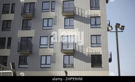 Vue de dessous du nouveau bâtiment résidentiel en briques blanches.Fragment d'une maison d'appartement en brique blanche avec balcons et lanternes de rue contre Banque D'Images