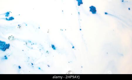 Vue de dessus des encres colorées sèches tombant dans une substance liquide blanche.Magnifique fond irisé de poudre verte, bleue et rose en fluide blanc Banque D'Images