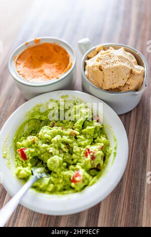 Au-dessus de la vue rapprochée du plat de guacamole dans un bol blanc fait avec de l'avocat vert mûr, des tomates et du piment rouge de bosse de pois chiches tartiner comme nourriture de déjeuner d'en-cas se Banque D'Images