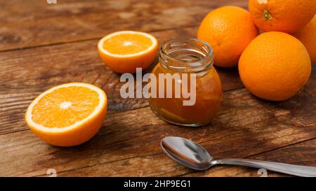 Pot de confiture d'orange et une cuillère en métal sur fond de bois depuis la vue de dessus. Marmelade d'orange maison, confiture au sirop épais. Banque D'Images