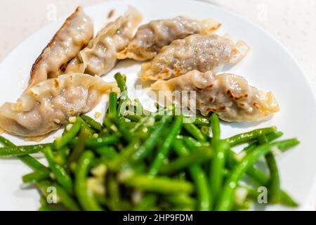 Gyoza de bœuf japonais ou coréen ou boulettes asiatiques mandu sur plaque blanche avec macro de haricots verts Banque D'Images