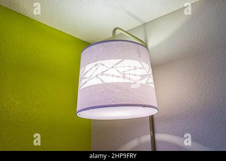 Lampe moderne de plus près dans la chambre d'hôtel nuit illuminée avec des couleurs vert violet lilas décoration murale peint coin Banque D'Images