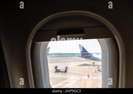 Vue aérienne à angle élevé depuis le plan de l'avion en vol américain avec fenêtre ouverte en verre sur la piste de l'aéroport avec d'autres avions Banque D'Images