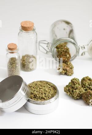 Gros plan des bourgeons de marijuana médicale, broyeur, bouteilles en verre, fond blanc Banque D'Images