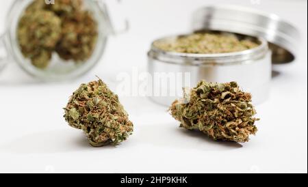 Gros plan des bourgeons de marijuana médicale, broyeur, bouteilles en verre, fond blanc Banque D'Images