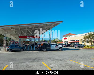 Kissimmee, Floride - 9 février 2022 : vue panoramique sur le magasin de proximité et la station-service de Wawa avec ravitaillement en voiture. Banque D'Images