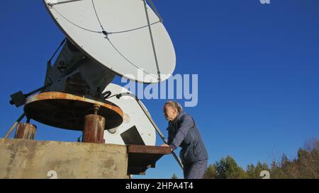 Une femme étudiante-opérateur de l'institut de physique terrestre solaire surveille les équipements de communication dans un ordinateur portable. Radiotélescope solaire à faisceau unique. DIM Banque D'Images