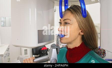 Médecin pour prendre une image scanner 3D tomographie des dents et de la mâchoire dans la clinique dentaire de laboratoire moderne. Une infirmière féminine montre à la patiente une machin à rayons X. Banque D'Images