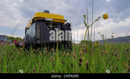 Gros plan du travail de générateur d'électricité mobile au gaz diesel sur l'herbe. Le générateur portable alimenté par carburant à essence fournit un courant électrique pendant Banque D'Images