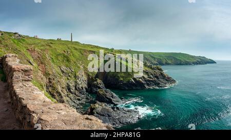 Mer Atlantique bleu et vert calme en été, cheminée de mine d'étain et bâtiments miniers ruinés sur les falaises, soleil sur les rochers déchiquetés sous les falaises Banque D'Images