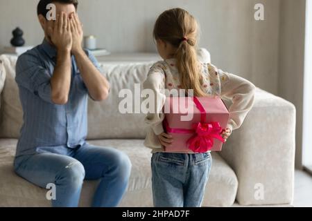 Petite fille d'âge préscolaire enfant tenant un cadeau surprise préparé derrière le dos Banque D'Images