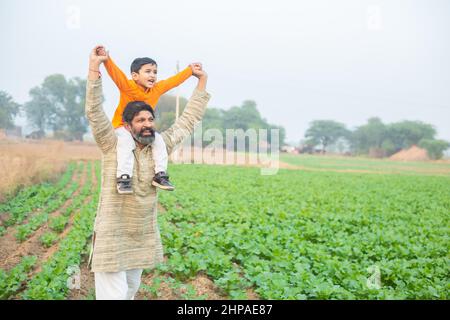 Heureux fils indiens assis sur l'épaule de père ayant le plaisir dans le domaine agricole, passer du temps libre ensemble dans la ferme, enfant de garçon profiter de l'enfance avec l'homme o Banque D'Images