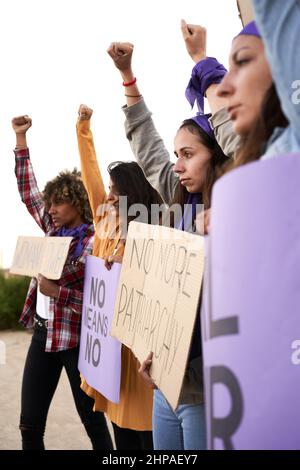 Photo verticale d'un groupe de femmes marchant sur la route en signe de protestation. Une jeune femme tient un signe de protestation sur l'autonomisation des femmes. Banque D'Images