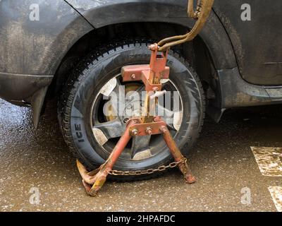 Tula, Russie - 3 janvier 2021 : installation de la capture d'un camion-manipulateur sur la roue d'une voiture Banque D'Images