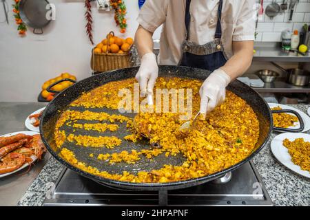Cuisinez en servant une paella de fruits de mer (paella de marisco), Valence, Espagne Banque D'Images
