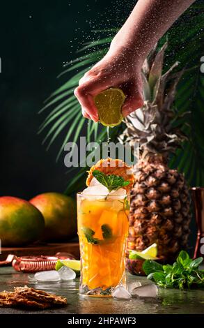 Cocktail d'été avec vodka, jus d'ananas, mangue, glace. Boisson longue ou boisson froide. Main de barman presse le jus de lime, mouvement congelé et vol dro Banque D'Images