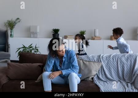 Une jeune mère afro-américaine stressée se sente fatiguée des enfants méchants. Banque D'Images