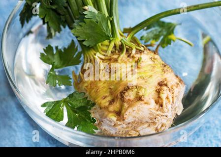 Tubercule de céleri cru avec feuille dans un bol en verre avec eau. Banque D'Images